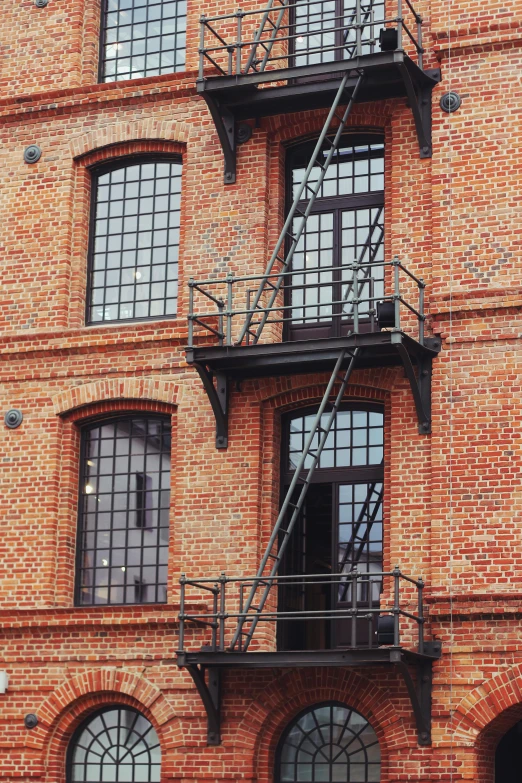 a red brick building with a fire escape ladder, a photo, pexels contest winner, steel window mullions, bay area, warehouses, brown