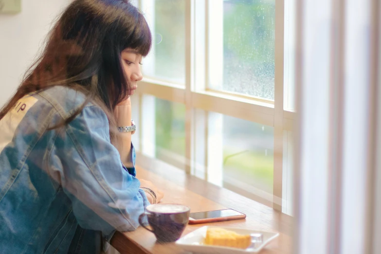 a woman sitting at a table in front of a window, a picture, by Eizan Kikukawa, trending on pexels, portrait of depressed teen, using a magical tablet, asian female, sitting on a mocha-colored table