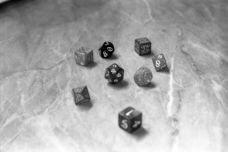 a bunch of dice sitting on top of a table, a black and white photo, by David Palumbo, dau-al-set, baldurs gate, marbled, tri - x, grainy