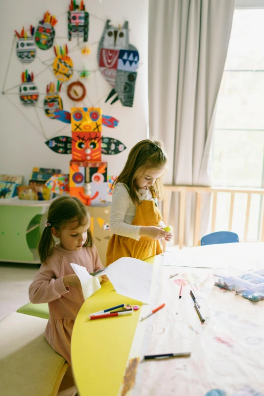 a couple of little girls sitting at a table, a child's drawing, inspired by Karel Appel, pexels, paper decoration, studying in a brightly lit room, gif, toy room