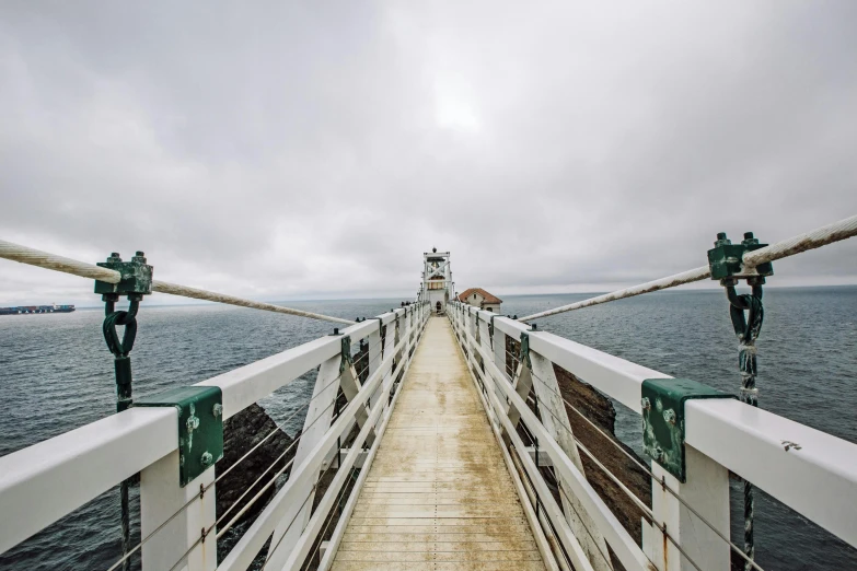 a bridge over a body of water with a lighthouse in the distance, unsplash contest winner, happening, slight overcast, gopro photo, 2 5 6 x 2 5 6 pixels, fan favorite