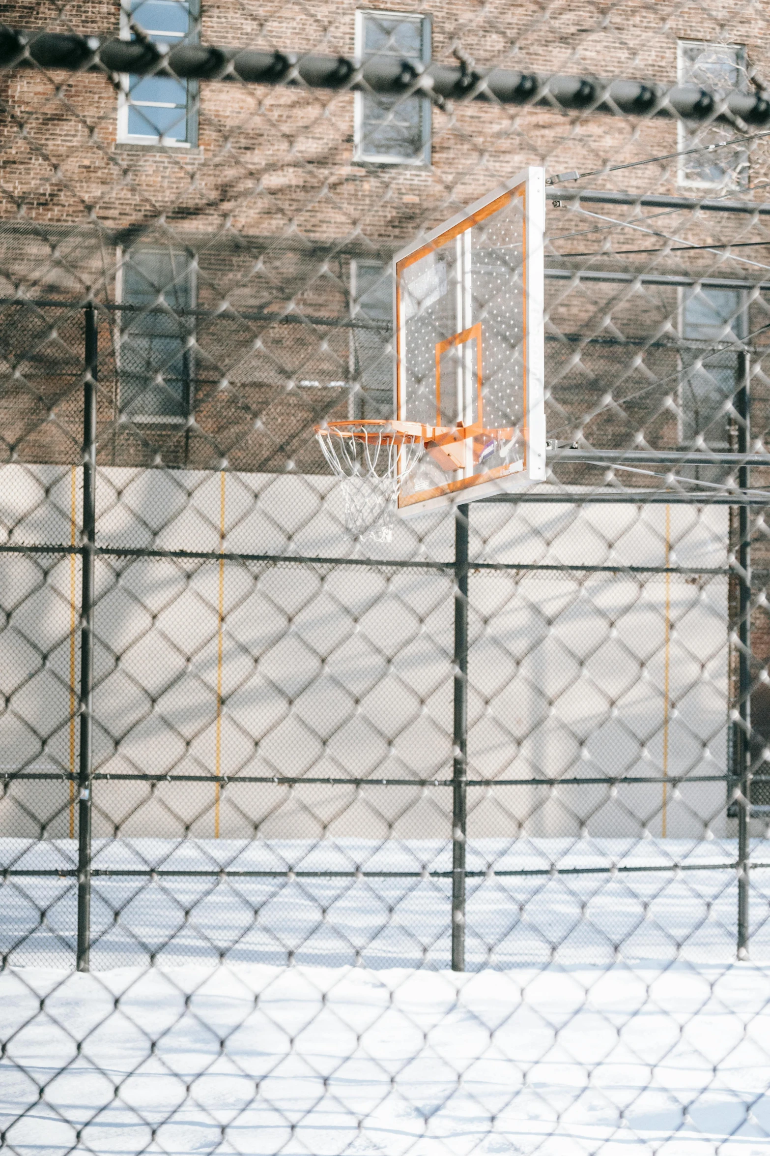 a basketball court surrounded by a chain link fence, by Dan Scott, square, shot from a distance, freeze frame, jamel shabazz