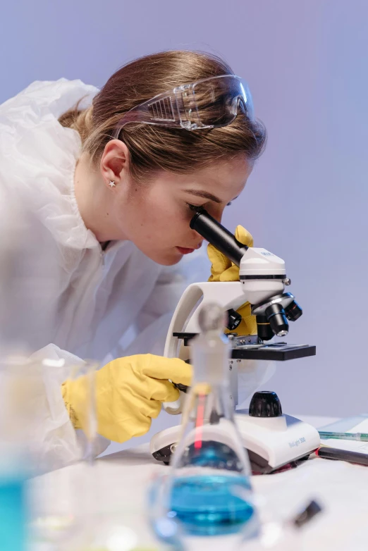 a woman in a lab coat looking through a microscope, sterile colours, thumbnail, gold, live