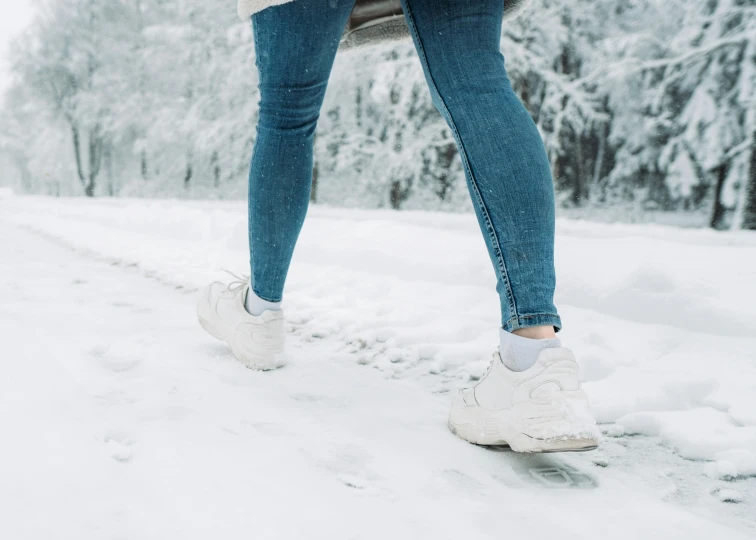 a close up of a person walking in the snow, wearing white sneakers, avatar image, wearing jeans, leggings