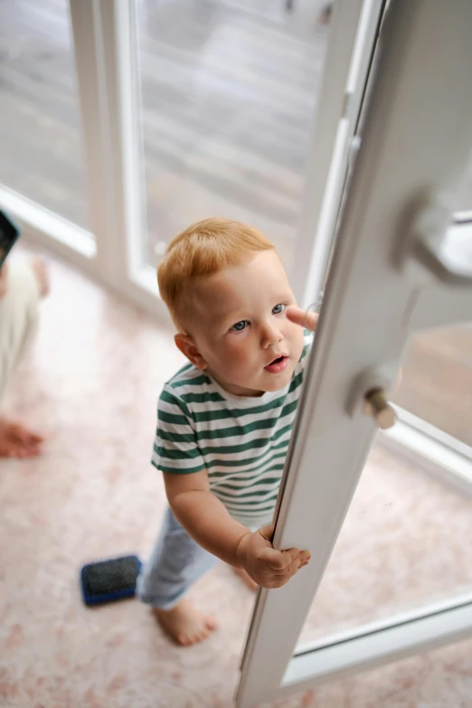 a little boy that is standing in front of a door, next to a window, up-close, as well as scratches, they might be crawling