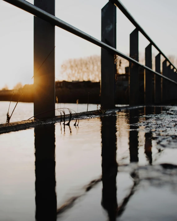 the sun is setting over a body of water, unsplash, art photography, wet concrete, railing along the canal, flooded ground, low quality photo