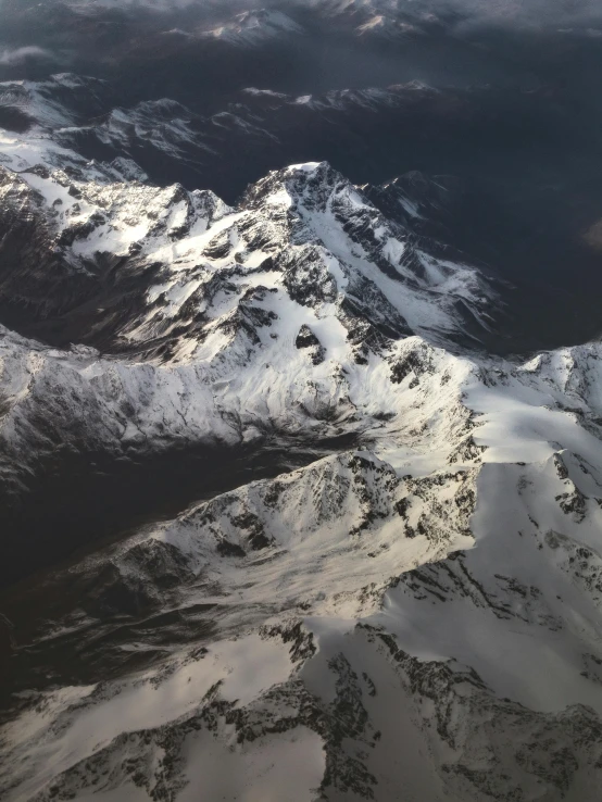 a view of snow covered mountains from an airplane, by Muggur, highly detailed # no filter, journalism photo