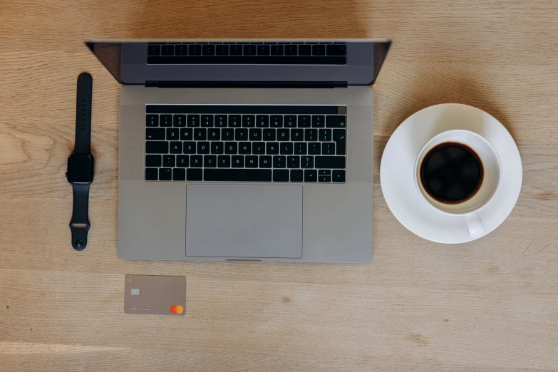 a laptop computer sitting on top of a wooden table next to a cup of coffee, by Romain brook, pexels contest winner, minimalism, pair of keycards on table, circular, dark grey and orange colours, bird's eye