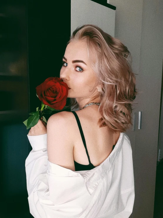 a woman holding a rose up to her face, inspired by Elsa Bleda, trending on pexels, better known as amouranth, short curly blonde haired girl, russian girlfriend, 🎀 🧟 🍓 🧚