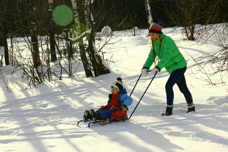 a woman pulling a child on a sled in the snow, pexels contest winner, bright nordic forest, avatar image, blue print, a green