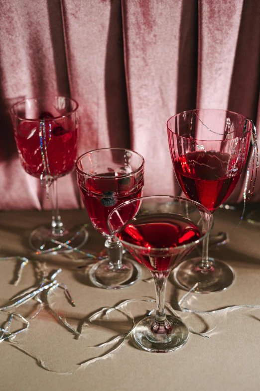 a group of wine glasses sitting on top of a table, a still life, in crimson red, featuring rhodium wires, embroidered velvet, curated collection