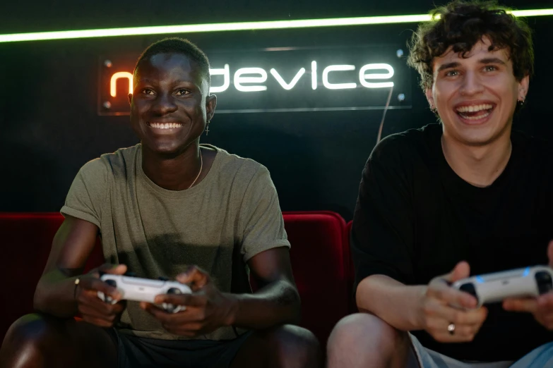 a couple of men sitting on top of a red couch, holding controller, adut akech, edin durmisevic, profile image