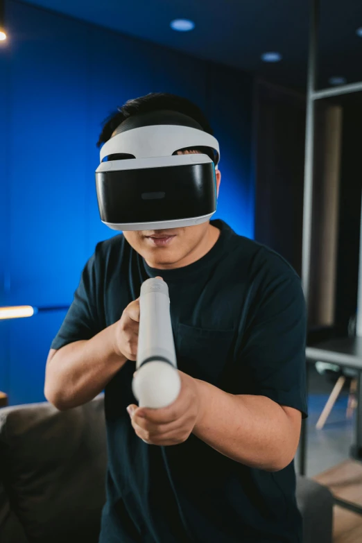 a man in a black shirt holding a video game controller, inspired by Zhu Da, interactive art, vr helmet, on ps5, holding a light saber, shot with sony alpha 1 camera