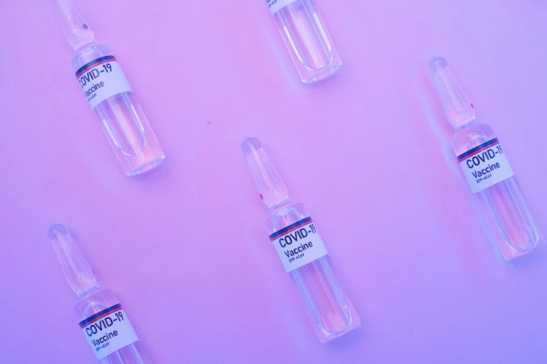 a group of vials sitting on top of a pink surface, trending on pexels, syringe, blue and purple colour scheme, looking from shoulder, sprites