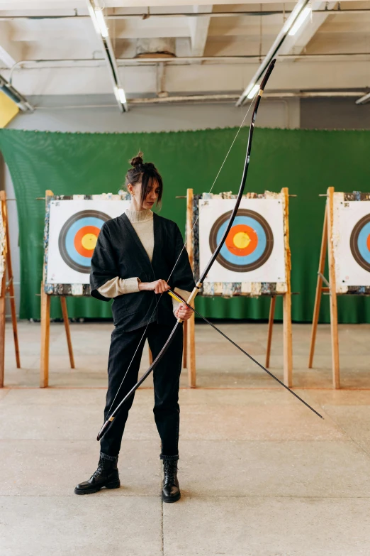 a man in a suit holding a bow and arrow, by Marina Abramović, trending on pexels, academic art, woman holding recurve bow, in a dojo, real life size, camp