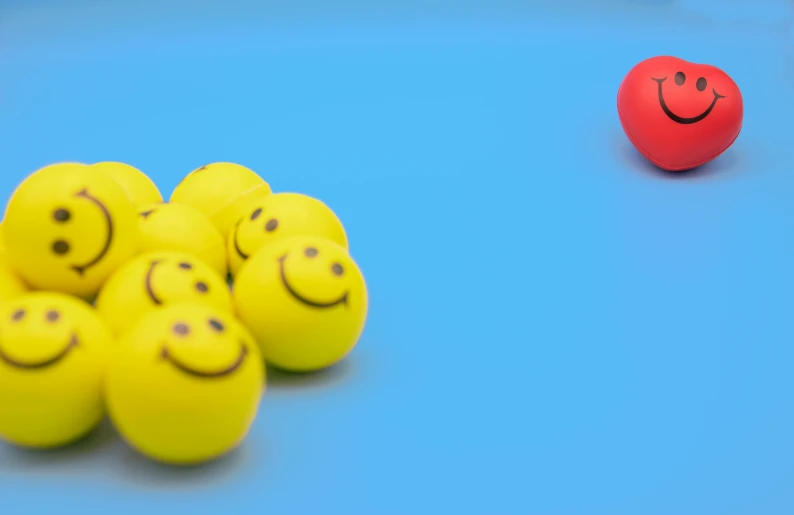 a bunch of yellow balls with smiley faces on them, a picture, by Emma Andijewska, figuration libre, brand colours are red and blue, taken with sony alpha 9, relaxed. blue background, schools