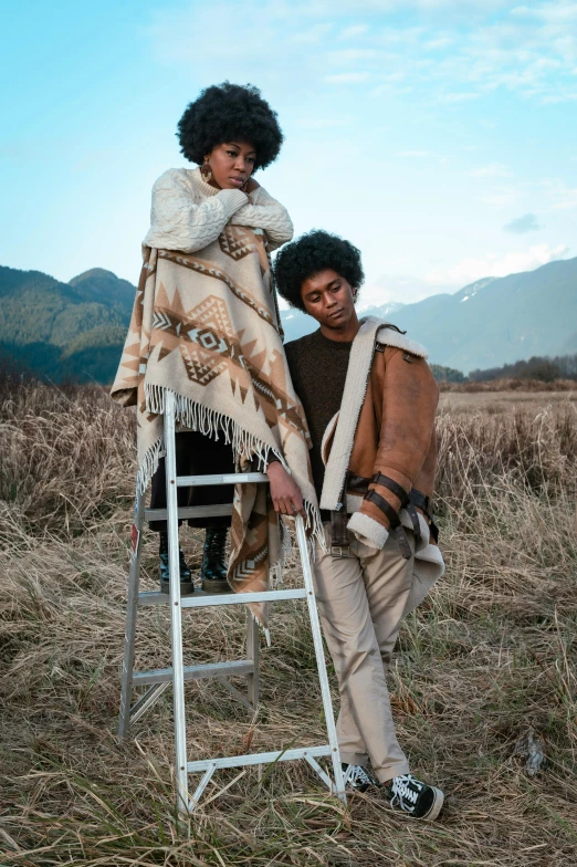 two people sitting on a ladder in a field, a portrait, by Jessie Algie, trending on pexels, renaissance, haida, wearing desert poncho, brown skin, ready to model