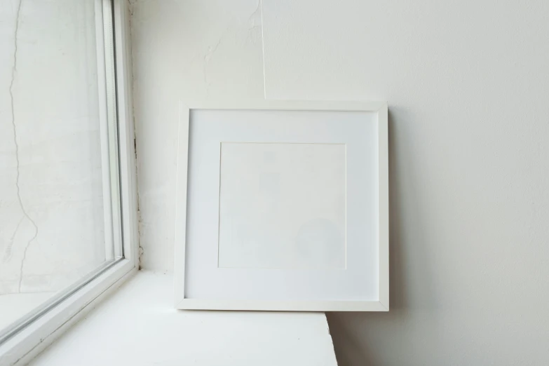 a picture frame sitting on top of a window sill, a minimalist painting, unsplash, square, white finish, studio photograph, in 2 0 1 2
