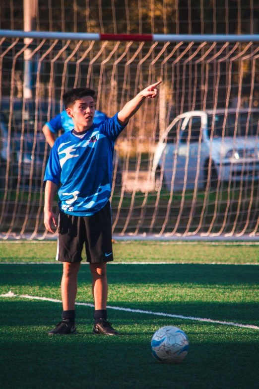 a young man standing next to a soccer ball on a field, by Robbie Trevino, pexels contest winner, happening, pointing, teen boy, asian male, gif