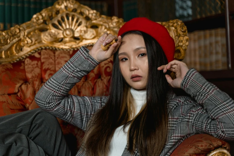 a woman sitting on a couch wearing a red hat, trending on pexels, cai xukun, a young woman as genghis khan, upscale photo, beanie