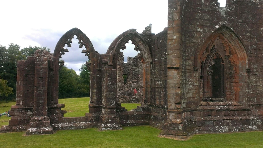 a large stone building sitting in the middle of a lush green field, by Alison Watt, pexels contest winner, romanesque, buttresses, rust, paisley, thumbnail
