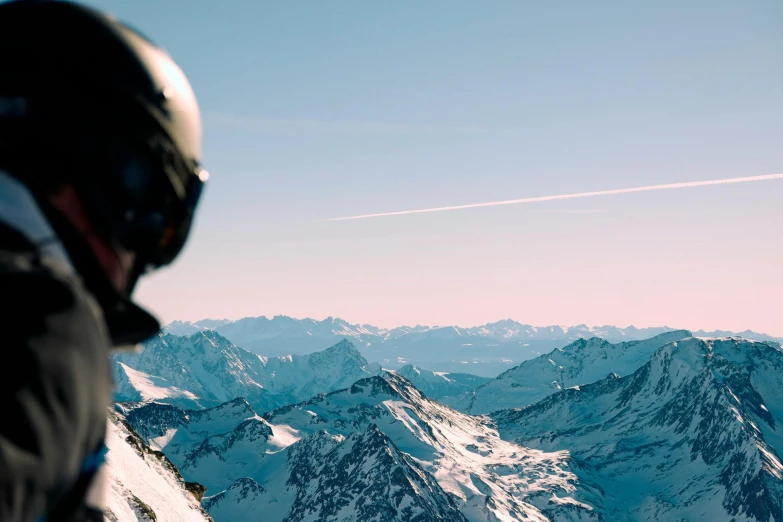 a man riding a snowboard down the side of a snow covered slope, an album cover, by Matthias Weischer, pexels contest winner, private press, helicopter footage over city, looking off into the distance, helmet view, **cinematic