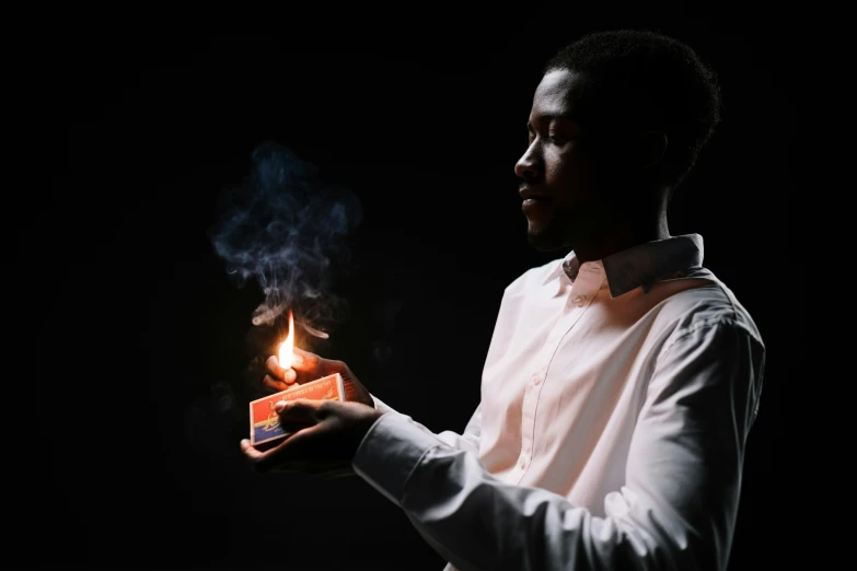 a man holding a lit cigarette in his hand, an album cover, pexels contest winner, holding a candle, african man, high quality upload, profile picture 1024px