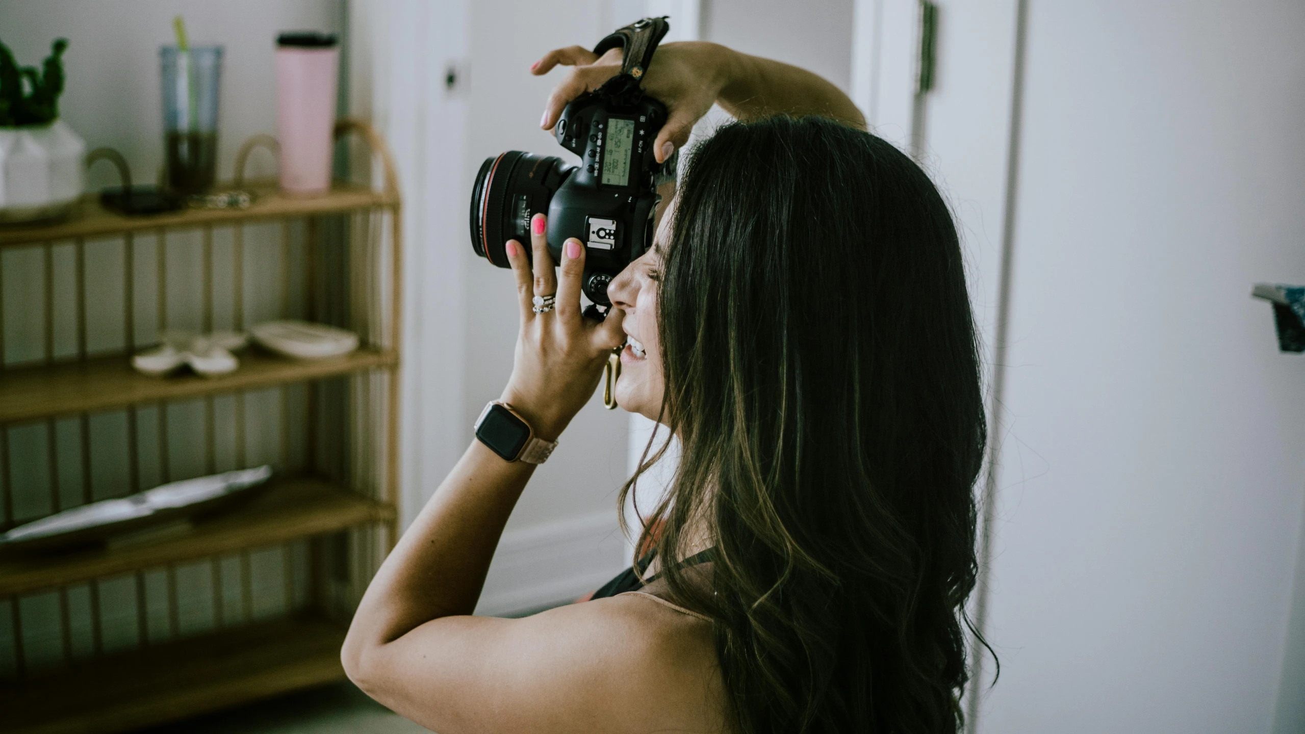 a woman holding a camera up to her face, pexels contest winner, photoshoot for skincare brand, looking from behind, indoor picture, body and headshot