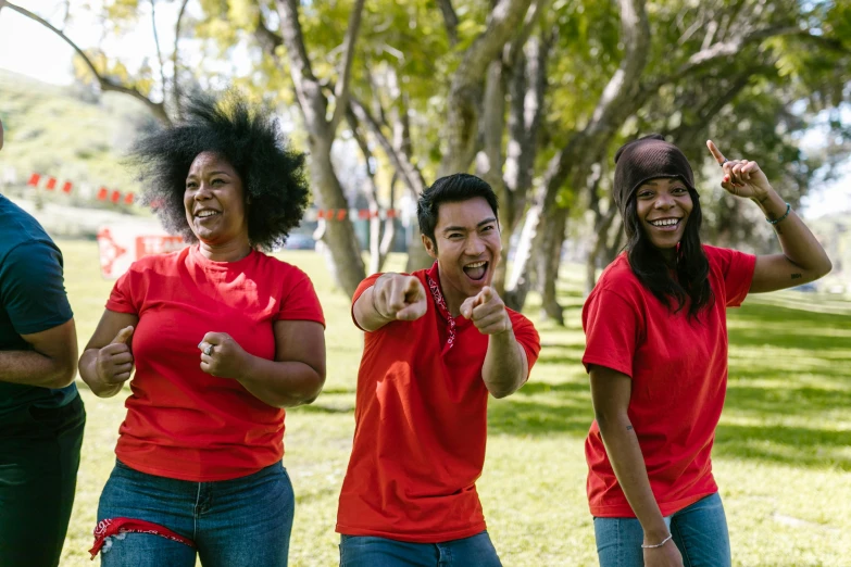 a group of women standing on top of a lush green field, pexels contest winner, happening, red t-shirt, smiling and dancing, at a park, a handsome