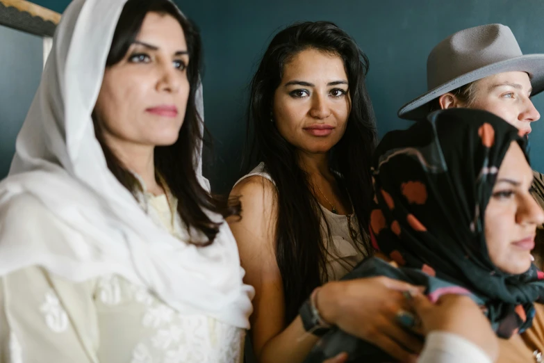 a group of people sitting next to each other, a portrait, trending on unsplash, hurufiyya, wearing a head scarf, motherly, videogame still, middle eastern details