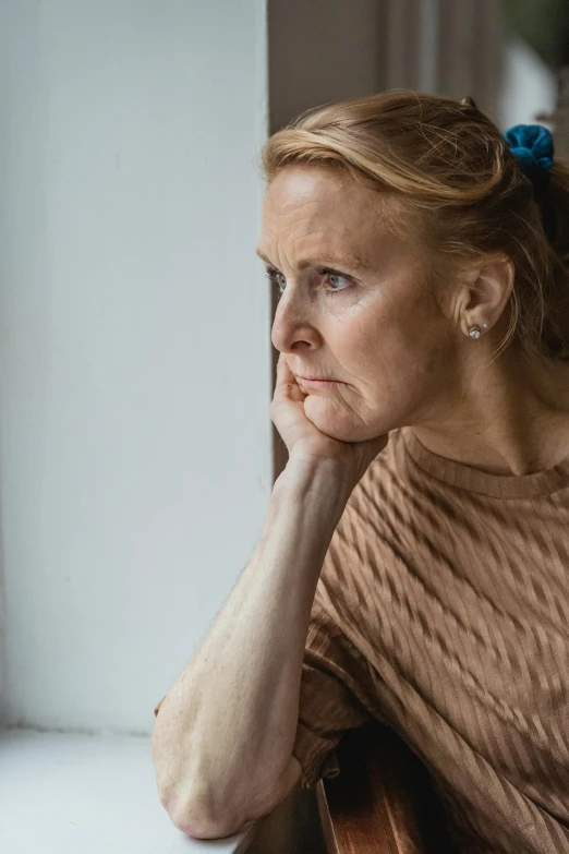 a woman sitting on a bench looking out a window, a portrait, trending on reddit, worried, middle aged, close up of a blonde woman, concerned expression