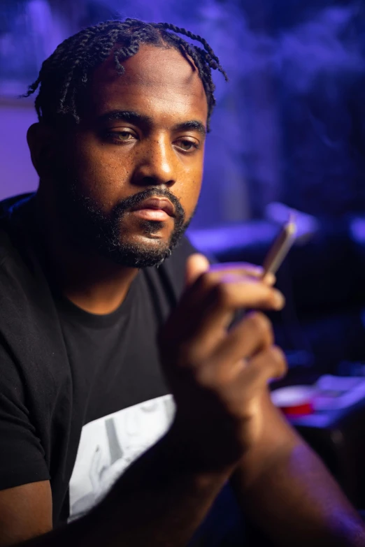 a close up of a person holding a cell phone, an album cover, dramatic smoking pose, riyahd cassiem, sitting at his desk, dark lighting