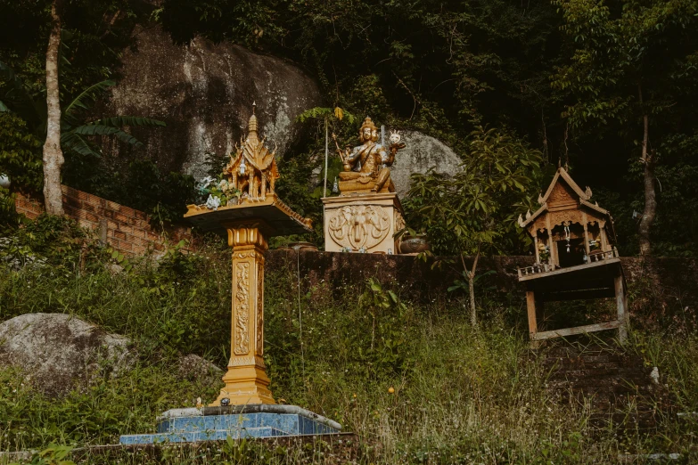 a group of statues sitting on top of a lush green hillside, by Lee Loughridge, pexels contest winner, pagoda with a lot of wind chimes, thumbnail, dark warm light, gold