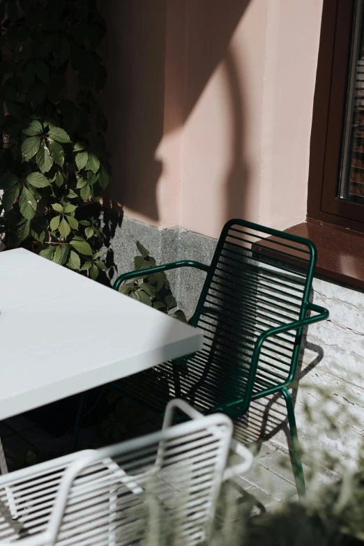 a white table and chairs on a patio, pexels contest winner, dark green color scheme, warsaw, subsurface scandering, in sunny weather