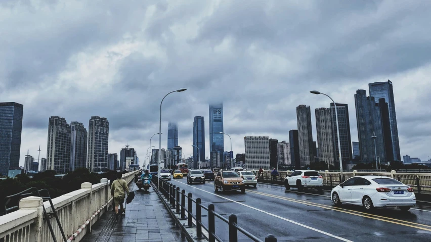 a street filled with lots of traffic next to tall buildings, a picture, inspired by Cheng Jiasui, pexels contest winner, hyperrealism, cloudy overcast sky, standing on a bridge, wet climate, instagram picture