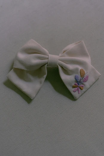 a close up of a bow on a table, by Sailor Moon, floral embroidery, taken in 1 9 9 7, 王琛, cream