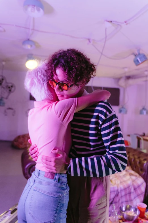 a couple of people that are hugging each other, inspired by Nan Goldin, pexels, visual art, dayglo pink, finn wolfhard, brightly lit purple room, pink glasses