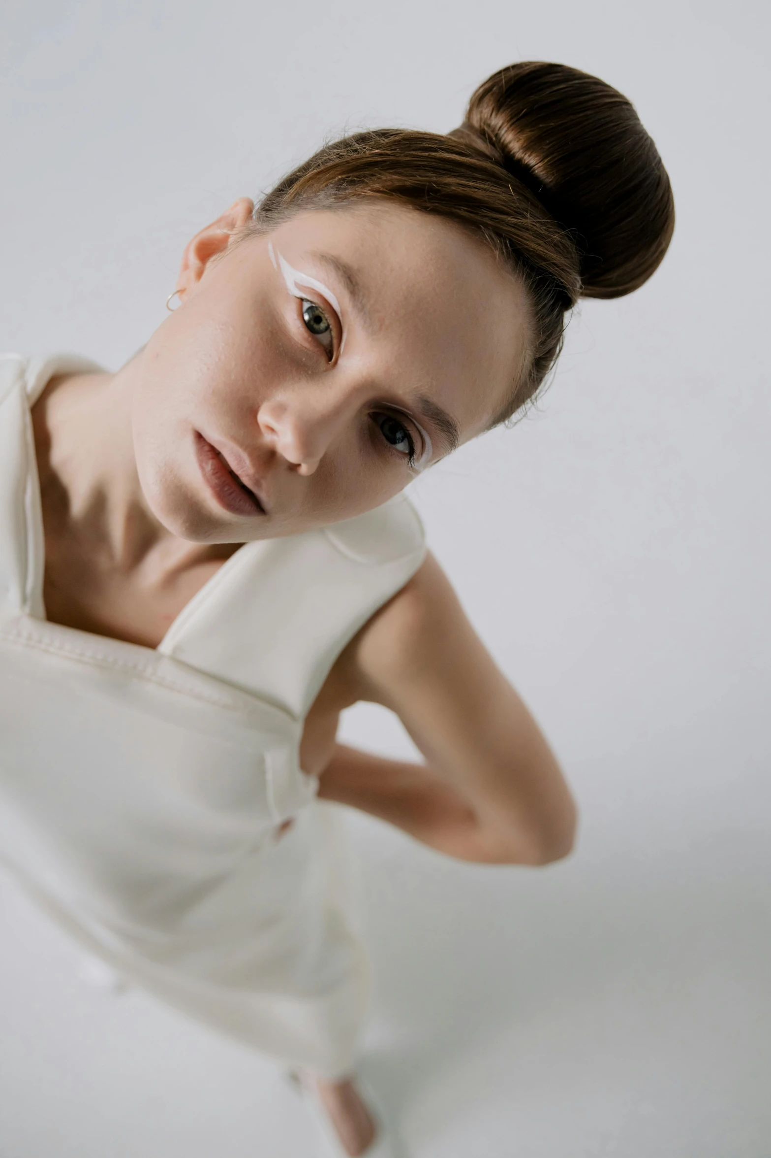 a woman in a white dress posing for a picture, inspired by Anna Füssli, trending on pexels, bauhaus, white eyebrows, top down, neutral focused gaze, pale skin