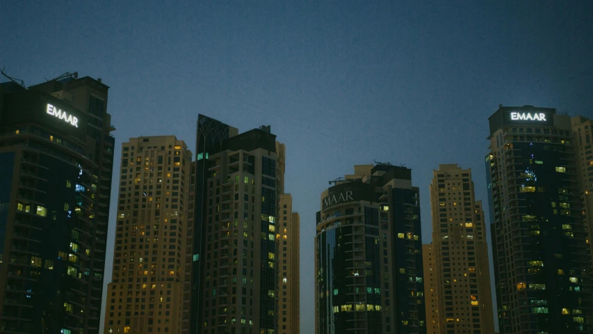 a group of tall buildings in a city at night, pexels contest winner, hyperrealism, dubai, poor lighting, low quality photo, late summer evening