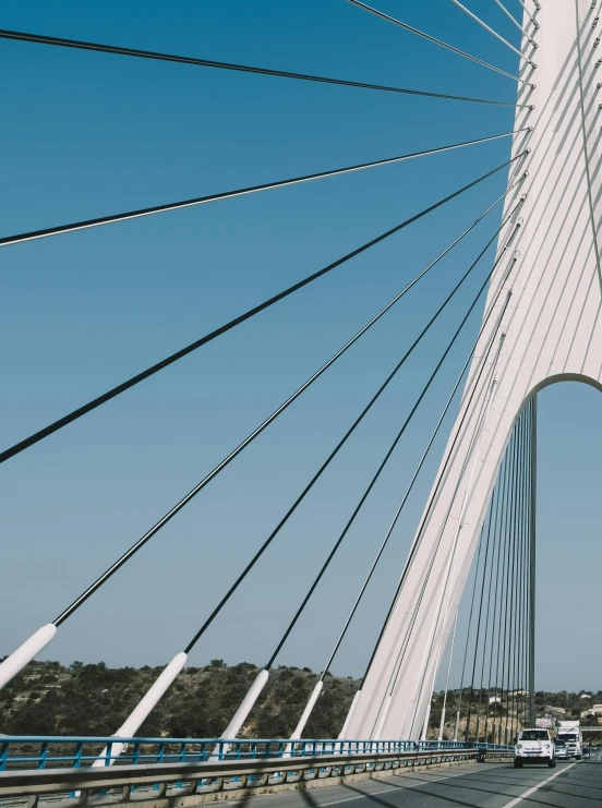 a group of cars driving across a bridge, inspired by Christo, pexels contest winner, modernism, cables hanging, calatrava, white, medium closeup shot