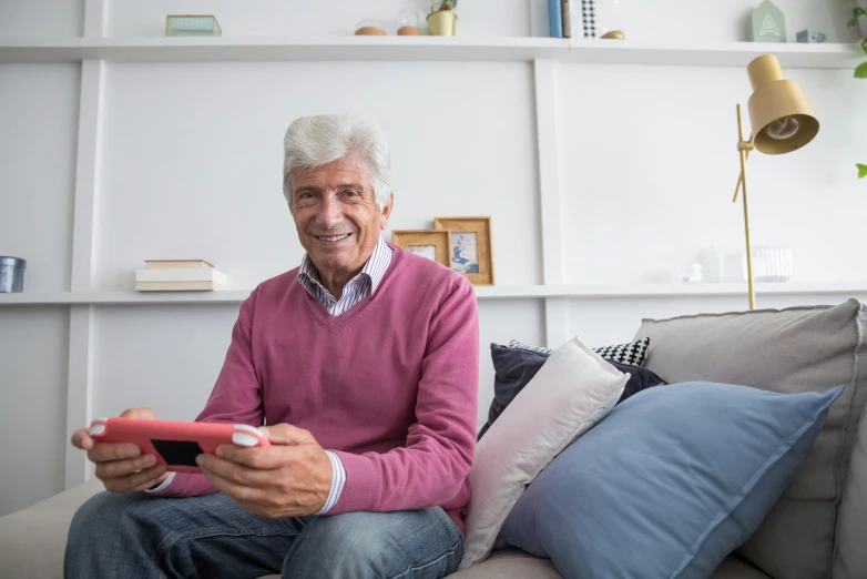 a man sitting on a couch holding a remote control, pexels contest winner, dark grey haired man, holding a nintendo switch, mimmo rottela, at home