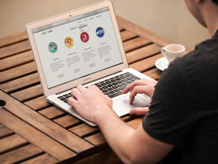 a man sitting at a table using a laptop computer, a digital rendering, pexels, award winning webdesign, 9 9 designs, a wooden, website banner