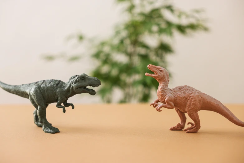 a couple of toy dinosaurs standing next to each other, inspired by Adam Rex, trending on unsplash, figuration libre, velociraptor, 2 colours, facing off in a duel, terracotta