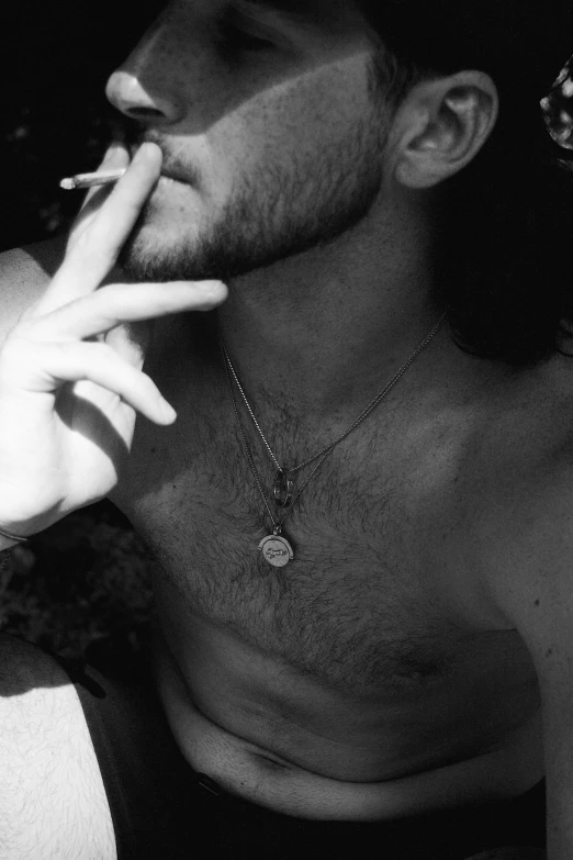 a black and white photo of a man smoking a cigarette, inspired by Antonin Artaud, shirtless :: high detail, ✨🕌🌙, petra collins, with his long black hair