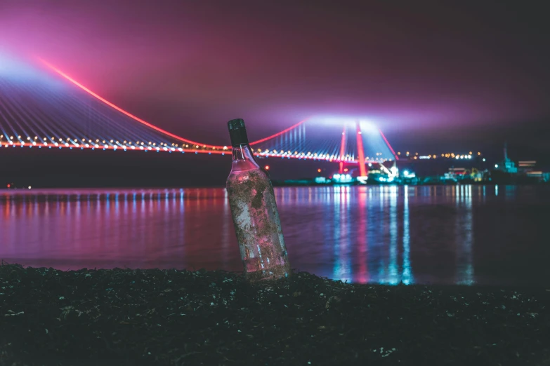 a body of water with a bridge in the background, a colorized photo, pexels contest winner, romanticism, bottle of vodka, nightlife, black sea, pink light