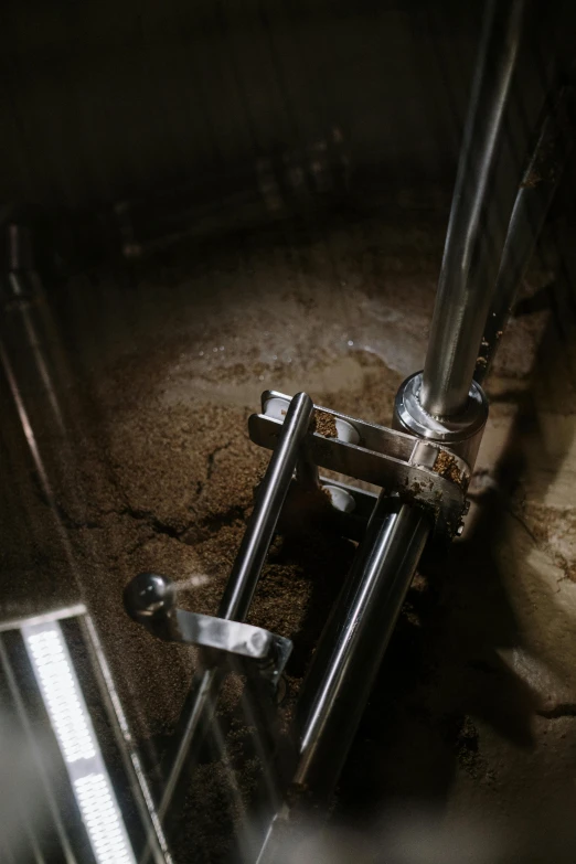 a toilet sitting inside of a bathroom next to a toilet paper dispenser, by Jacob Toorenvliet, unsplash, process art, industrial machinery, looking down from above, inside a beer glass, sand piled in corners