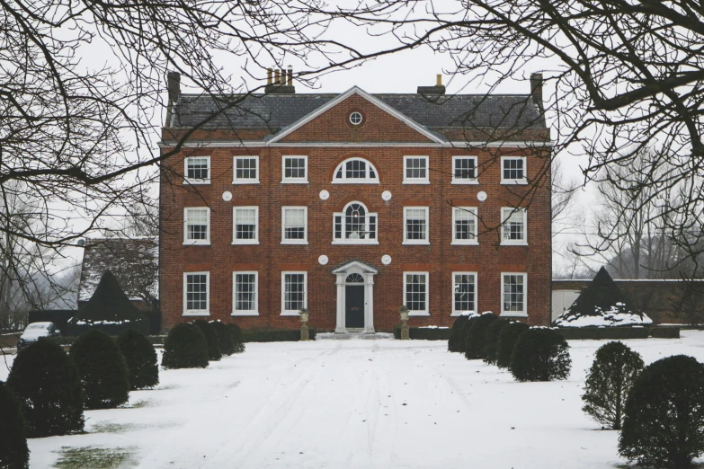 a large red brick building sitting on top of a snow covered field, inspired by Rachel Whiteread, pexels, 1 8 th century manor, exterior view, thom browne, grey