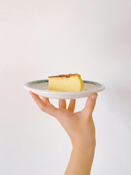 a person holding a plate with a piece of cake on it, by Eizan Kikukawa, arabesque, extra cheese, organic ceramic white, 4l, flan