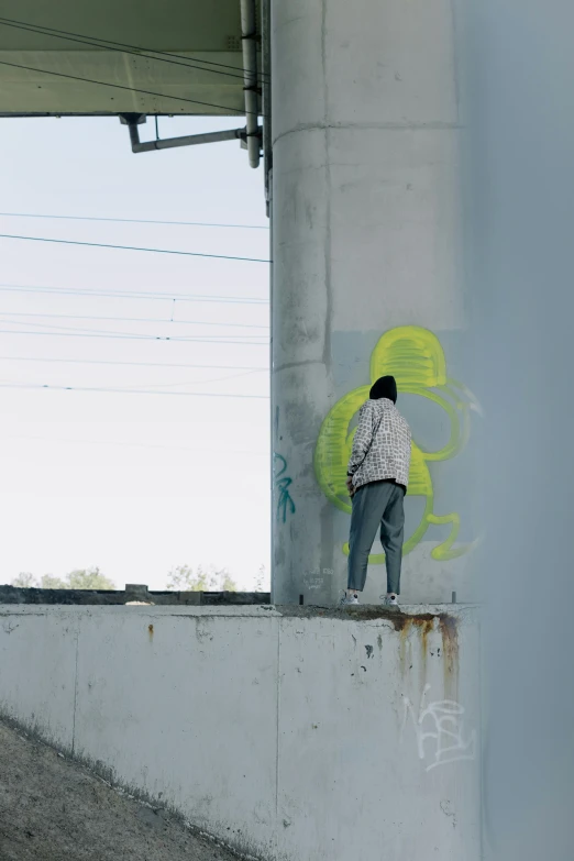 a man riding a skateboard on top of a cement wall, trending on pexels, graffiti, skinny female artist back view, white neon wash, “ painting, contemplating