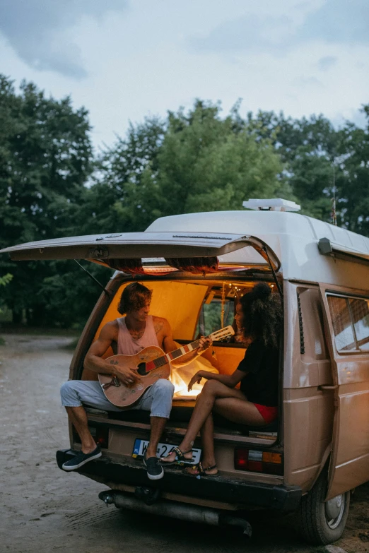 a couple of people sitting in the back of a van, unsplash contest winner, renaissance, jamming to music, campfire, 🚿🗝📝